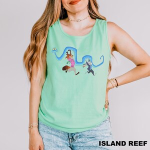 A woman wearing a green tank top with a cartoon character design and a necklace.