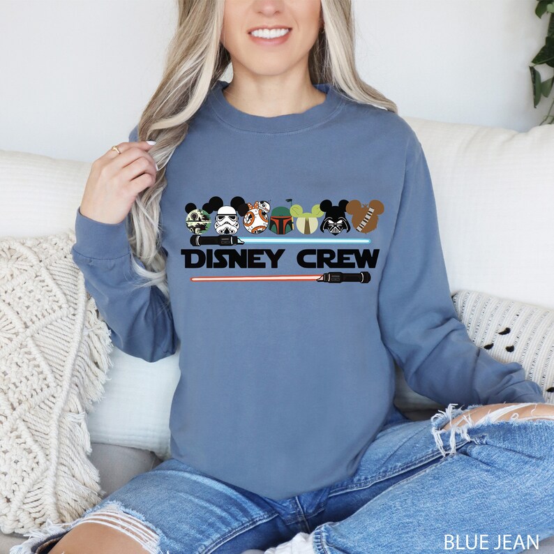 a woman sitting on a couch wearing a disney crew sweatshirt