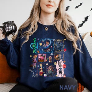 A woman wearing a navy blue sweatshirt with a collage of various cartoon characters and illustrations on it, including a character with a bat-like design.