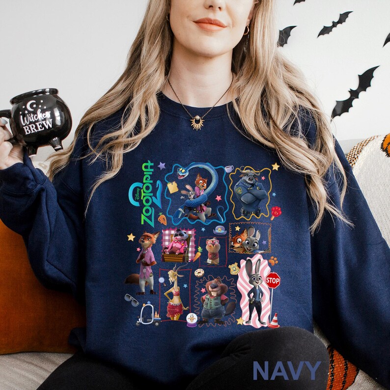 A woman wearing a navy blue sweatshirt with a collage of various cartoon characters and illustrations on it, including a character with a bat-like design.