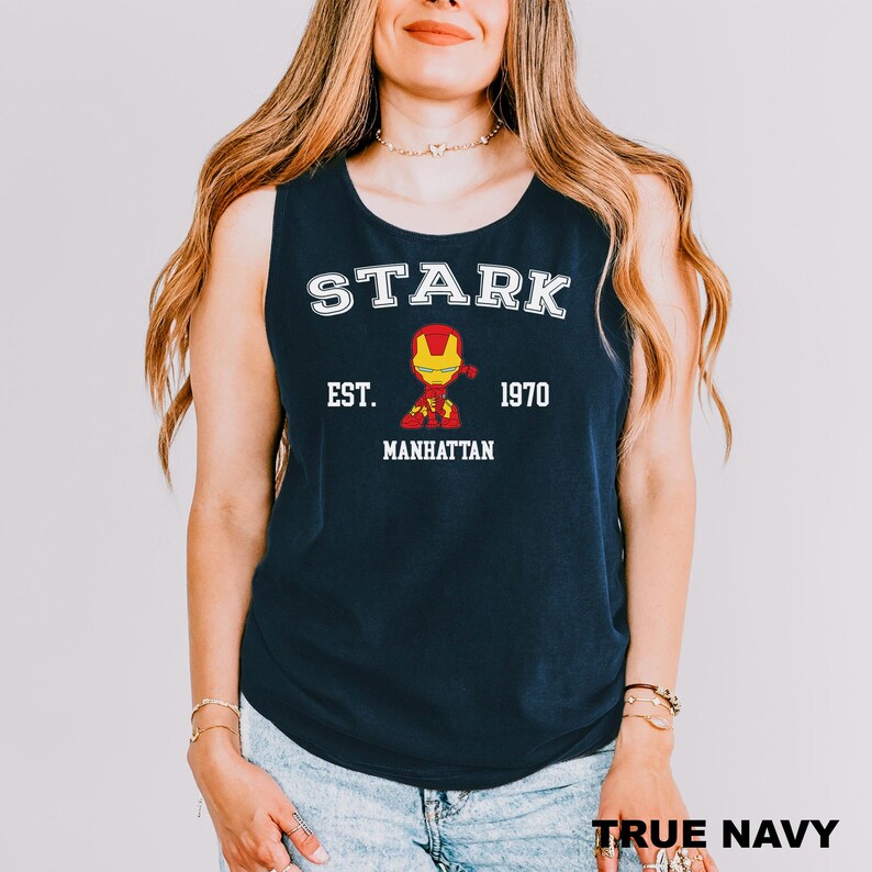 A woman wearing a navy blue tank top with the text "STARK EST. MANHATTAN 1970" and an illustration of Iron Man.