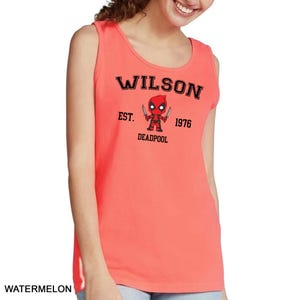 A woman wearing a red tank top with a graphic of a character from the Marvel Cinematic Universe, specifically Deadpool, printed on it.
