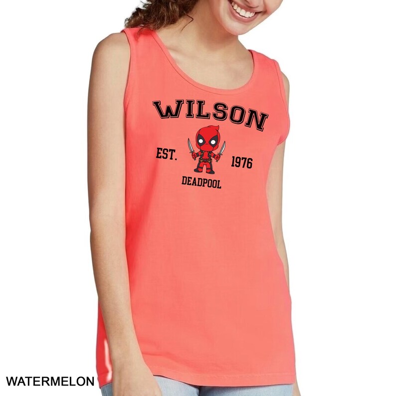 A woman wearing a red tank top with a graphic of a character from the Marvel Cinematic Universe, specifically Deadpool, printed on it.