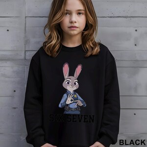 A young girl wearing a black sweatshirt with a cartoon rabbit character and the text "SIX SEVEN" printed on it.