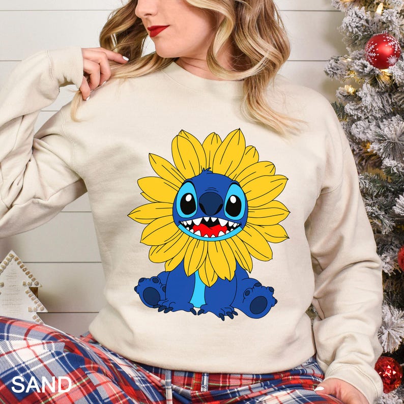 A woman wearing a white sweatshirt with a cartoon character of a blue and yellow flower on it.