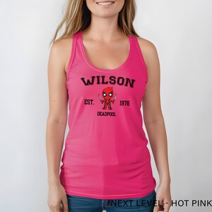 A woman wearing a pink tank top with a graphic of a character from the Marvel Cinematic Universe.
