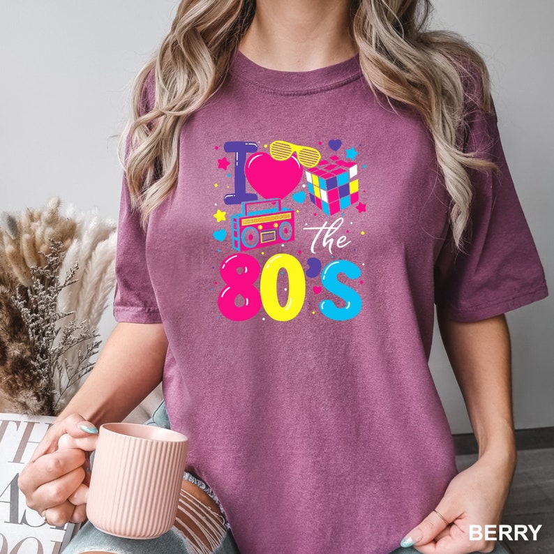 a woman is holding a coffee cup and wearing a t - shirt that says i
