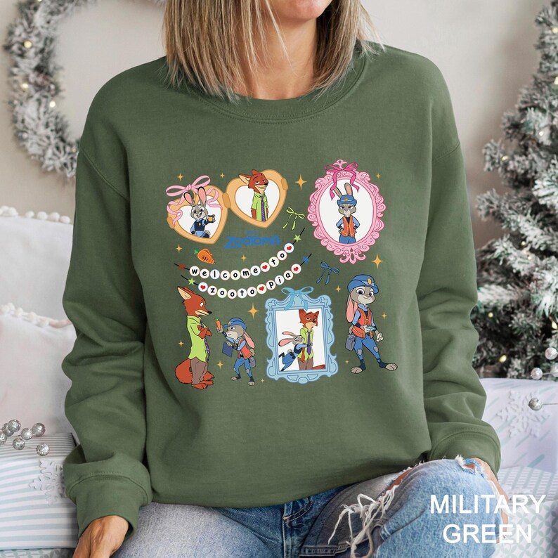 A woman wearing a green sweatshirt with a colorful graphic design featuring cartoon characters and various decorative elements.