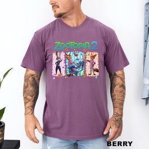 A man wearing a purple t-shirt with a graphic of characters from the animated film "Zootopia 2".