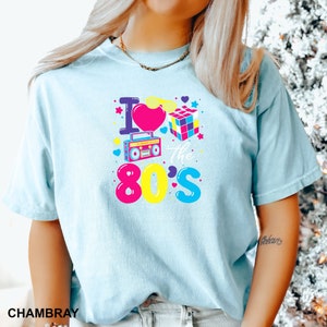 a woman wearing a blue shirt with the words i love the 80's on