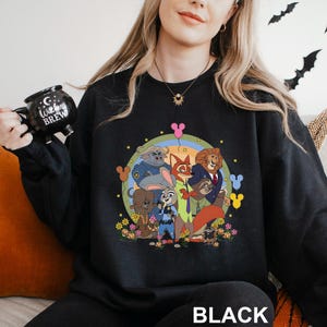 A woman wearing a black sweatshirt with a colorful graphic of cartoon characters from the Disney movie "Jumanji" on it.