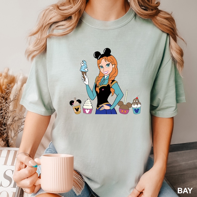 a woman holding a cup of coffee and a mickey mouse t - shirt