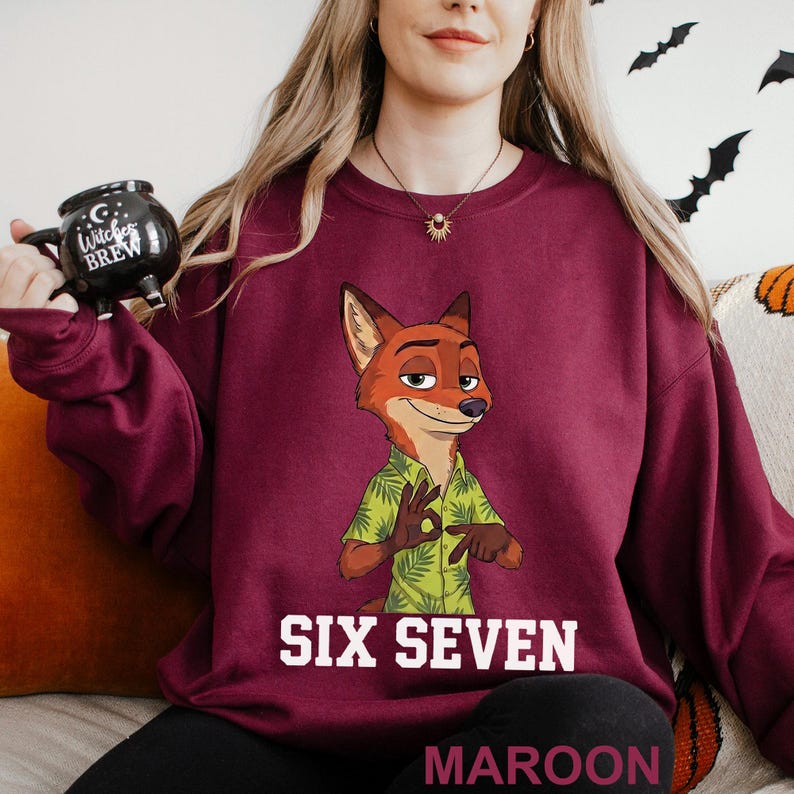 A woman wearing a purple sweatshirt with a cartoon image of a fox character and the text "SIX SEVEN MARoon" printed on it.