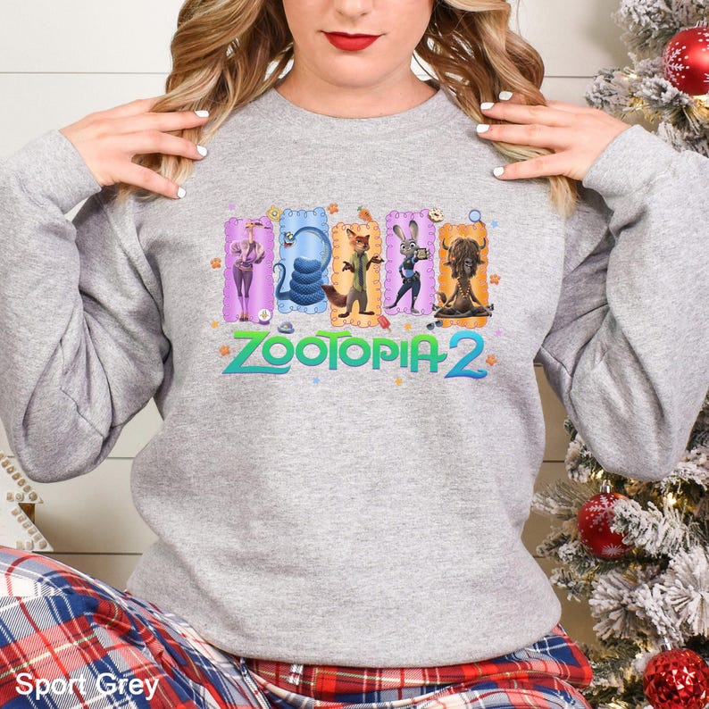 A woman wearing a grey sweatshirt with a colorful graphic of cartoon animal characters from the movie "Zootopia 2".