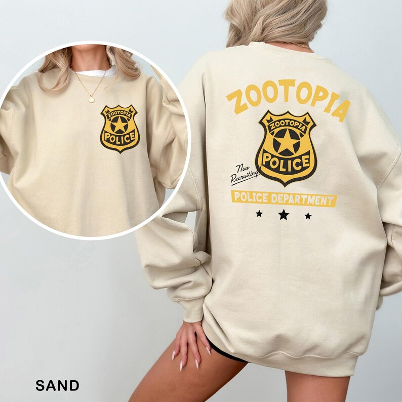 A woman wearing a beige sweatshirt with a police department logo on the back.