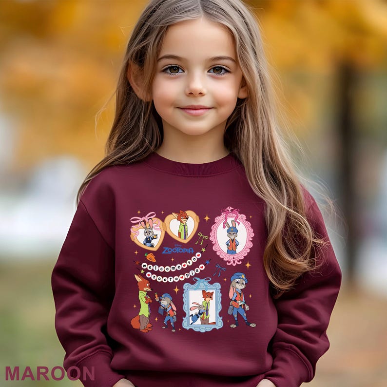 A young girl with long blonde hair wearing a maroon sweater with various cartoon characters and designs.