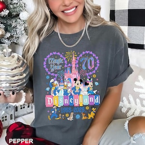 A woman wearing a gray t-shirt with a Disney theme graphic celebrating the 70th anniversary of Disneyland.