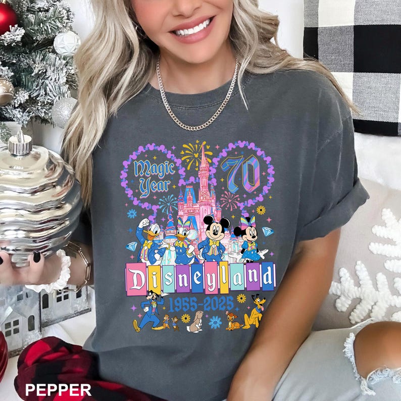A woman wearing a gray t-shirt with a Disney theme graphic celebrating the 70th anniversary of Disneyland.