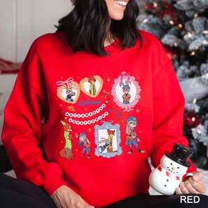 A woman wearing a red sweater with a cartoon character design, including a snowman and other festive elements, is holding a snowman toy.