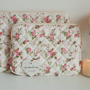 May include: Two quilted laptop sleeves with a floral rose pattern in pink and green on a cream background. The sleeves have a diamond pattern and a zipper closure. One sleeve is larger than the other. A heart-shaped tag reads "Cute Natural Design Handmade".