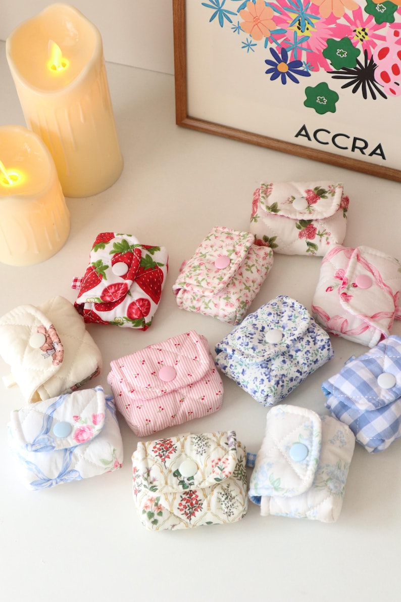 Pu&ograve; includere: Una collezione di piccole pochette in tessuto trapuntato con chiusure a scatto, caratterizzate da vari motivi tra cui fragole, stampe floreali e quadretti vichy blu. Ogni pochette &egrave; rettangolare e dotata di una patta.