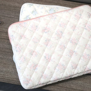 May include: Two quilted laptop cases with a floral pattern in pink and blue on a white background. The cases have a diamond pattern and a pink trim. A heart-shaped tag reads "Cute Natural Design".
