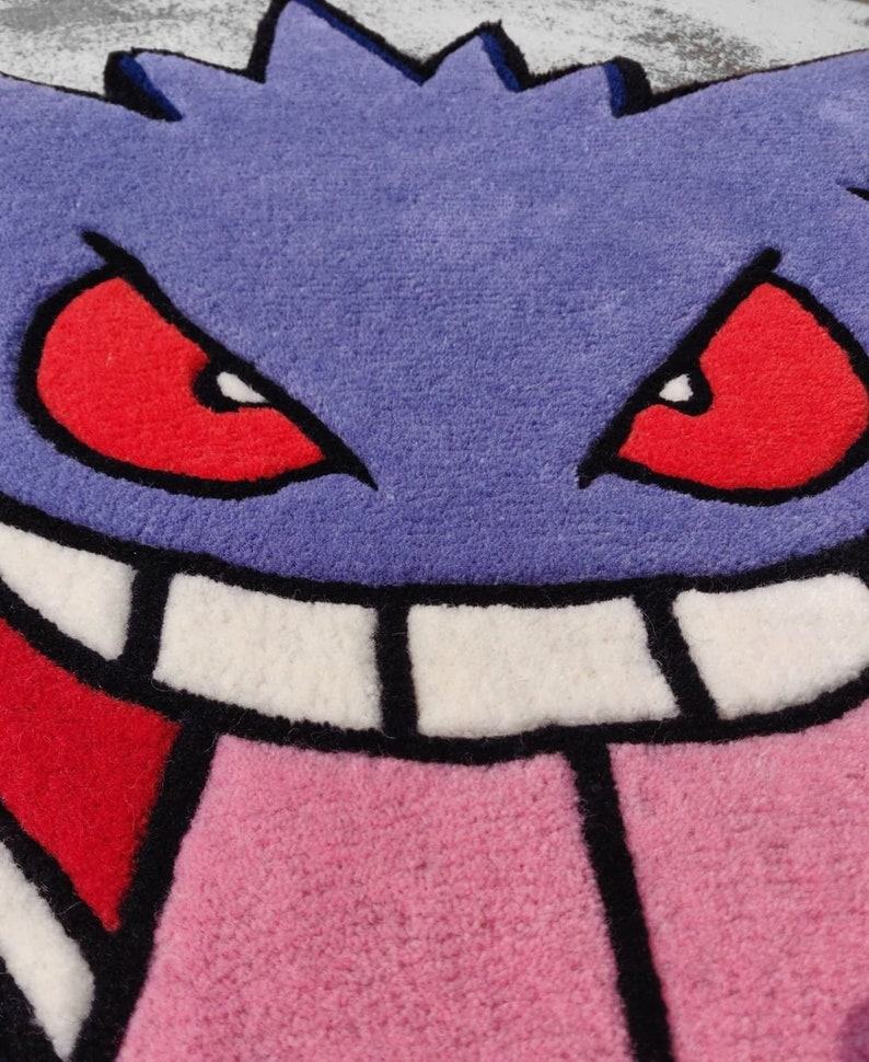 May include: A purple rug featuring a cartoon face with red eyes, a pink tongue, and white teeth. The rug has a jagged outline and a black border, creating a playful and vibrant design. This rug is perfect for a kid's room or a game room.