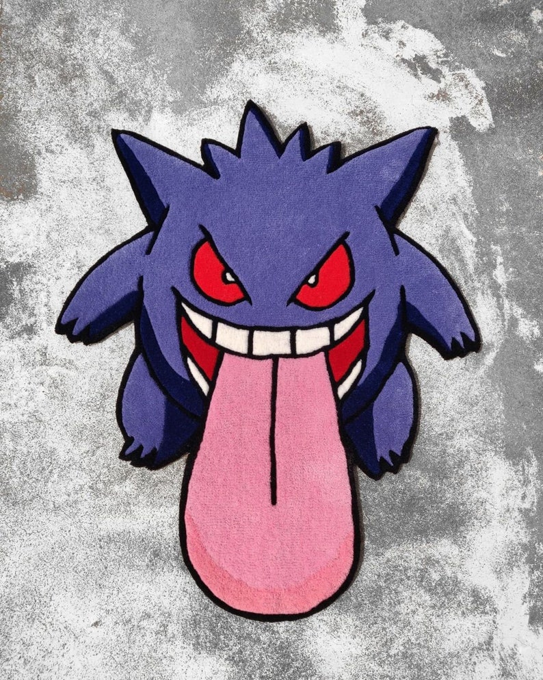 May include: A purple rug shaped like a cartoon character with a wide grin and a long pink tongue. The character has red eyes and a spiky head. The rug is on a gray surface.
