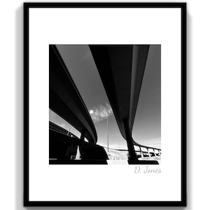 Puede incluir: Fotografía en blanco y negro de un paso elevado de autopista con un diseño curvo. La foto está tomada desde debajo del paso elevado, mirando hacia el cielo. La firma del fotógrafo, "D. Jones", está en la esquina inferior derecha.