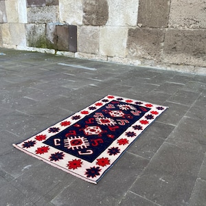 Könnte beinhalten: Drei cremefarbene Keramikbecher mit gesprenkelter Glasur. Jeder Becher zeigt ein handgemaltes Blumenmuster in Blau, Grün und Gelb. Die Becher haben eine schlichte, runde Form und einen bequemen Henkel.