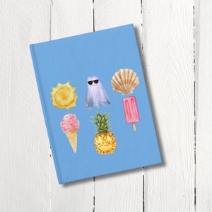 May include: A light blue journal featuring watercolor illustrations of summer icons. The cover includes a yellow sun, a ghost wearing sunglasses, a seashell, a pink popsicle, an ice cream cone, and a pineapple.