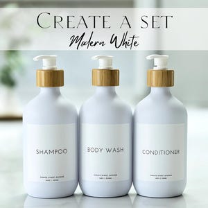 May include: Three white bottles with bamboo lids and pumps. The bottles are labeled "Shampoo", "Body Wash", and "Conditioner". The text "Create a Set Modern White" is at the top of the image.