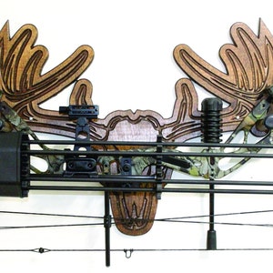 May include: A wooden moose head wall mount with a bow and arrow holder. The mount is made of dark wood and has a realistic moose head design. The bow and arrow holder is made of metal and has a black finish.