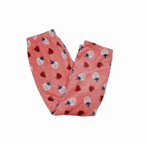 Puede incluir: Pantal&oacute;n de pijama rosa con estampado de fresas y corazones.