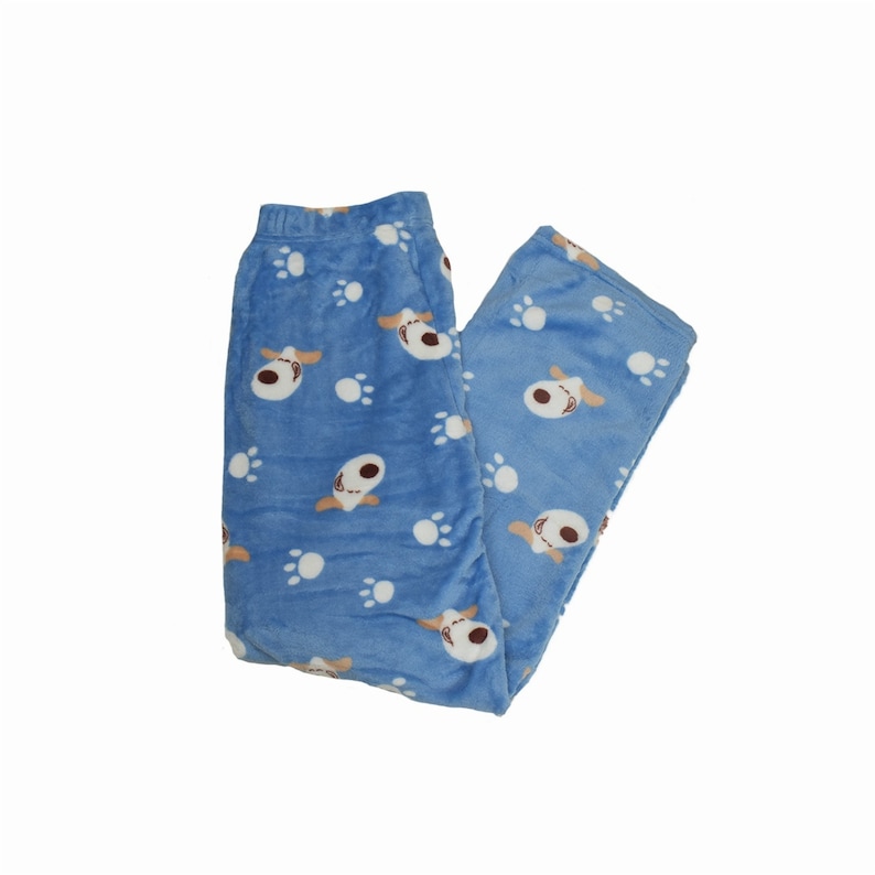 Puede incluir: Pantal&oacute;n de pijama azul con un estampado de huellas de perro y cara de perro blancas y marrones.
