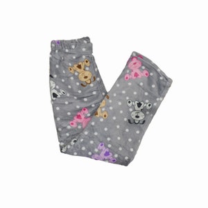 Puede incluir: Pantal&oacute;n de pijama de franela gris con un patr&oacute;n de lunares blancos y un estampado de perro de dibujos animados.