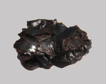 May include: A dark brown, almost black, resinous substance with a rough, uneven texture.