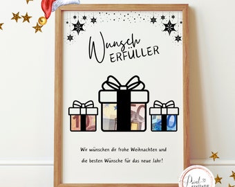 May include: A framed print with a festive theme. The artwork features three gift boxes with currency inside, and the German text "Wunsch Erfüller" at the top. The bottom text reads "Wir wünschen dir frohe Weihnachten und die besten Wünsche für das neue Jahr!"