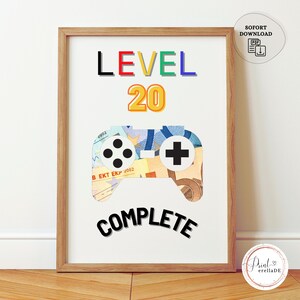 May include: A framed print with the text "LEVEL 20 COMPLETE" in black letters. The number 20 is in yellow and the word "LEVEL" is in red, green, and black. A colourful game controller made of paper money is below the text.