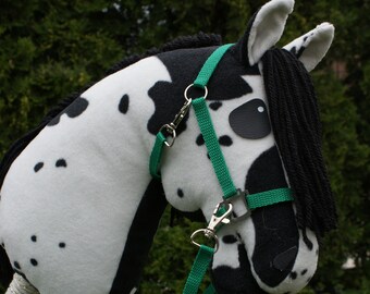 May include: A black and white spotted hobby horse with a green halter and lead rope. The horse has a black mane and tail.