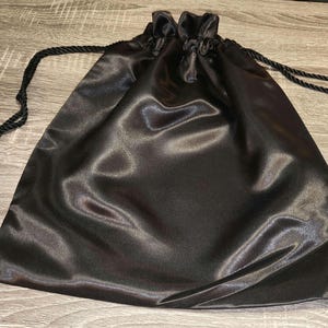 May include: A black satin drawstring bag with a tassel on each end of the cord.