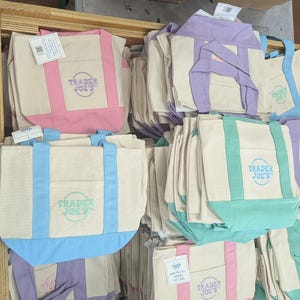 Könnte beinhalten: Eine weiße Keramik-Tasse mit schwarzem Henkel und dem Text "But First, Coffee" in fetter, schwarzer Schrift. Die Tasse steht vor einem verschwommenen Hintergrund, der eine gemütliche Umgebung suggeriert.