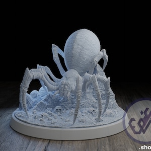 Puede incluir: Un modelo de araña impreso en 3D de color blanco con un cuerpo grande y redondo y ocho patas. La araña está posada sobre una base rocosa con calaveras y otros detalles.