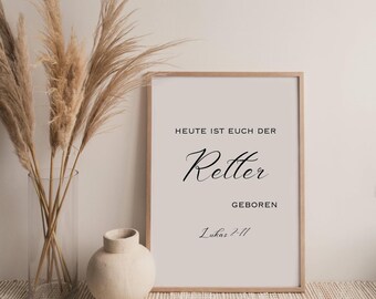 Puede incluir: Un estampado enmarcado con el texto "HEUTE IST EUCH DER Retter GEBOREN Lukas 2:11" en escritura negra. El estampado está en un marco de madera clara. Un jarrón con plantas secas y un jarrón pequeño de color crema están frente al estampado.