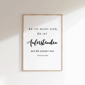 May include: A white framed print with black text that reads "ER IST NICHT HIER, ER IST AUFERSTANDEN WIE ER GESAGT HAT. MATTHAEUS 28:6"