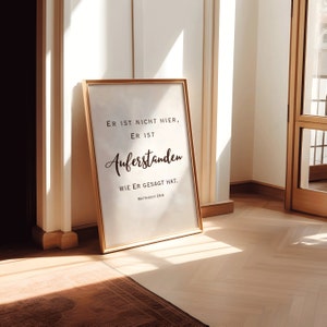 May include: A gold framed print with the text "ER IST NICHT HIER, ER IST AUFERSTANDEN WIE ER GESAGT HAT. MATTHAEUS 28:6" on a white background.