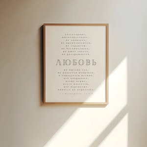 May include: A framed print with a white background and black text in Russian. The text reads "Love is patient, love is kind. It does not envy, it does not boast, it is not proud. It does not dishonor others, it is not self-seeking, it is not easily angered, it keeps no record of wrongs. Love does not delight in evil but rejoices with the truth. It always protects, always trusts, always hopes, always perseveres. Love never fails."  1 Corinthians 13:4-7