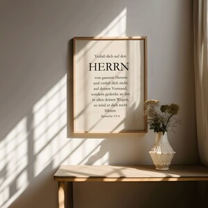 May include: A framed print with a beige background and black text. The text reads "Verlaß dich auf den HERRN von ganzem Herzen und verlaß dich nicht auf deinen Verstand, sondern gedenke an ihn in allen deinen Wegen, so wird er dich recht führen. Sprüche 3:5-6".