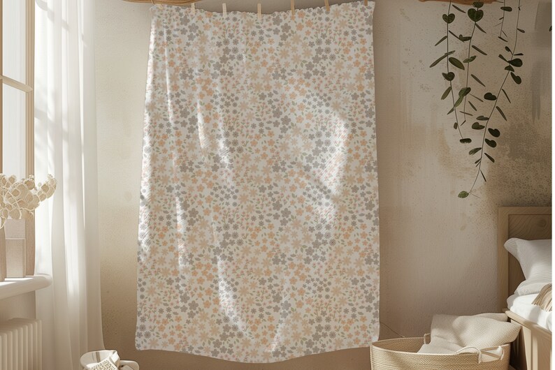 May include: A rectangular fabric panel featuring a dense, repeating floral pattern in soft shades of muted peach and light gray against a white background. The textile is suspended from a horizontal line by small wooden clips at the top edge.