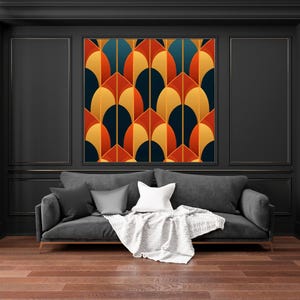 Puede incluir: Un sofá gris oscuro con almohadas blancas y grises y una manta blanca. Una impresión de arte geométrico con un patrón de formas naranjas, amarillas y azules cuelga en la pared detrás del sofá.